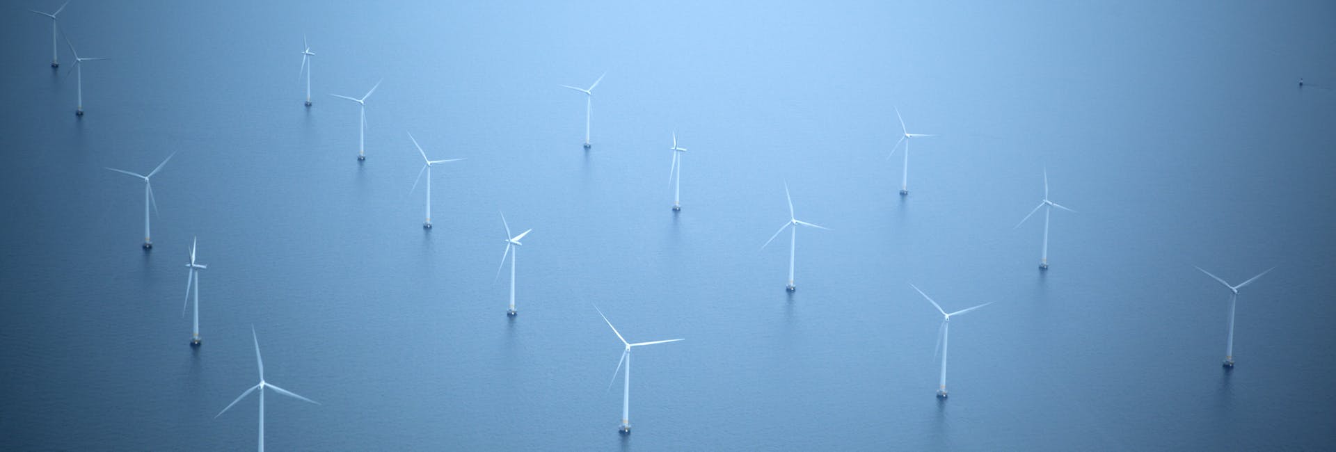 White wind turbines in the middle of the sea, with a boat in the background