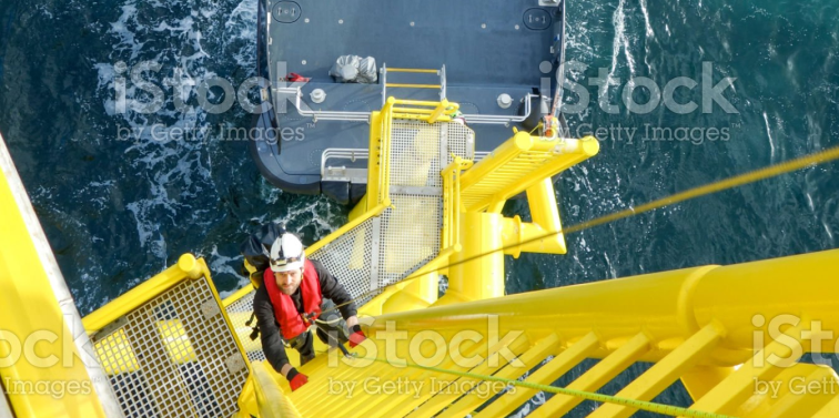 Man climbing up a yellow ladder on an oil rig, dark sea in the background